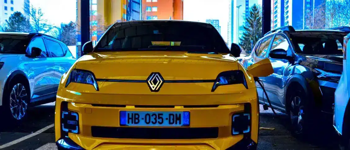 Renault 5 E-Tech jaune en charge sur une borne en pied d'immeuble