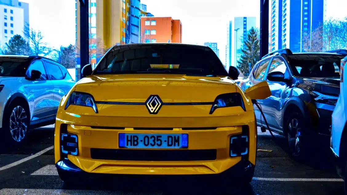 Renault 5 E-Tech jaune en charge sur une borne en pied d'immeuble