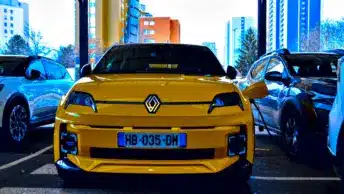 Renault 5 E-Tech jaune en charge sur une borne en pied d'immeuble